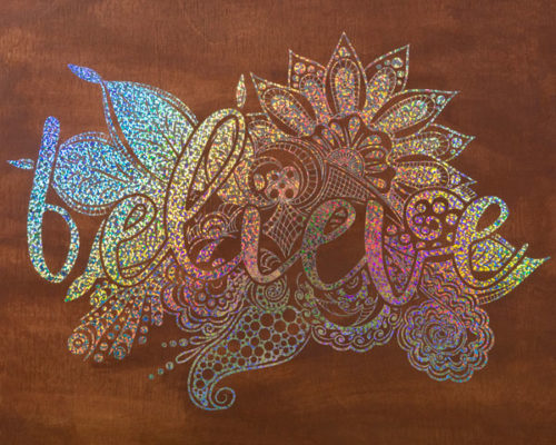 A wood board with a mandala style design and the word "believe" in Holo Mist Silver Holographic SpecialtyPSV™